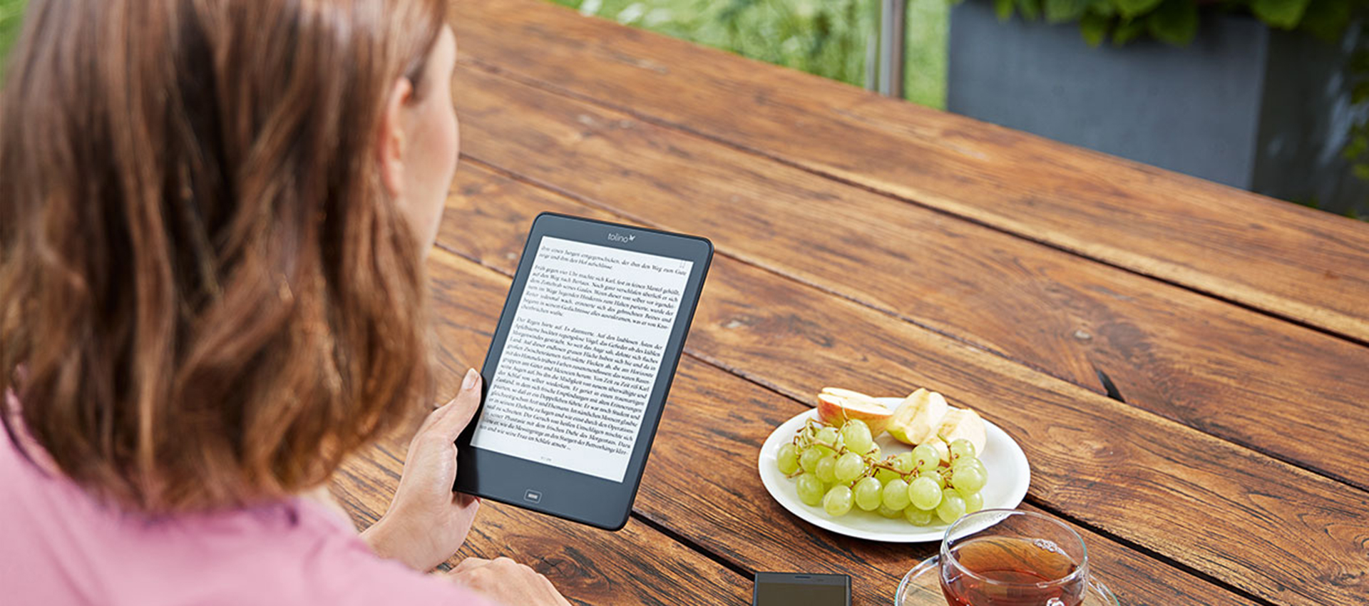 Frau am Tisch mit tolino-eReader.