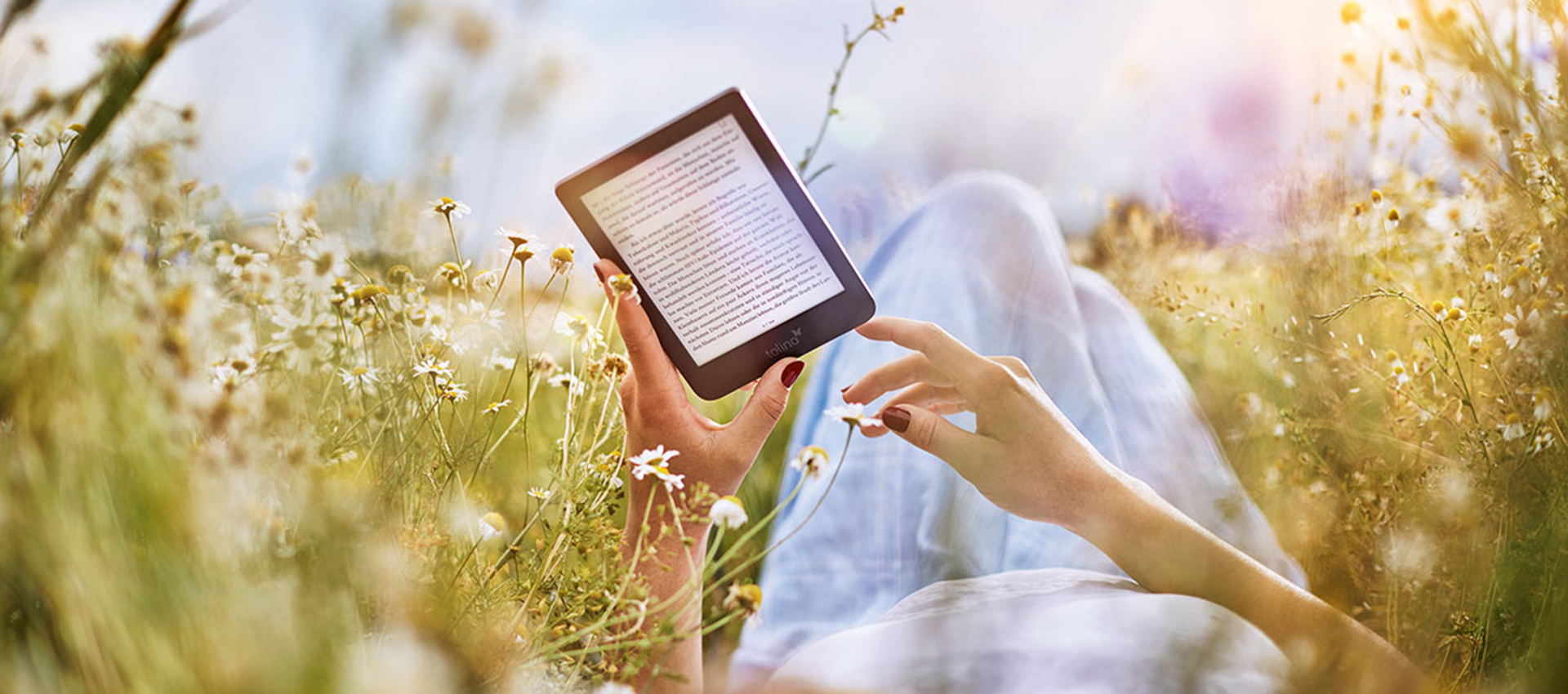 Person auf Wiese mit tolino-eReader.