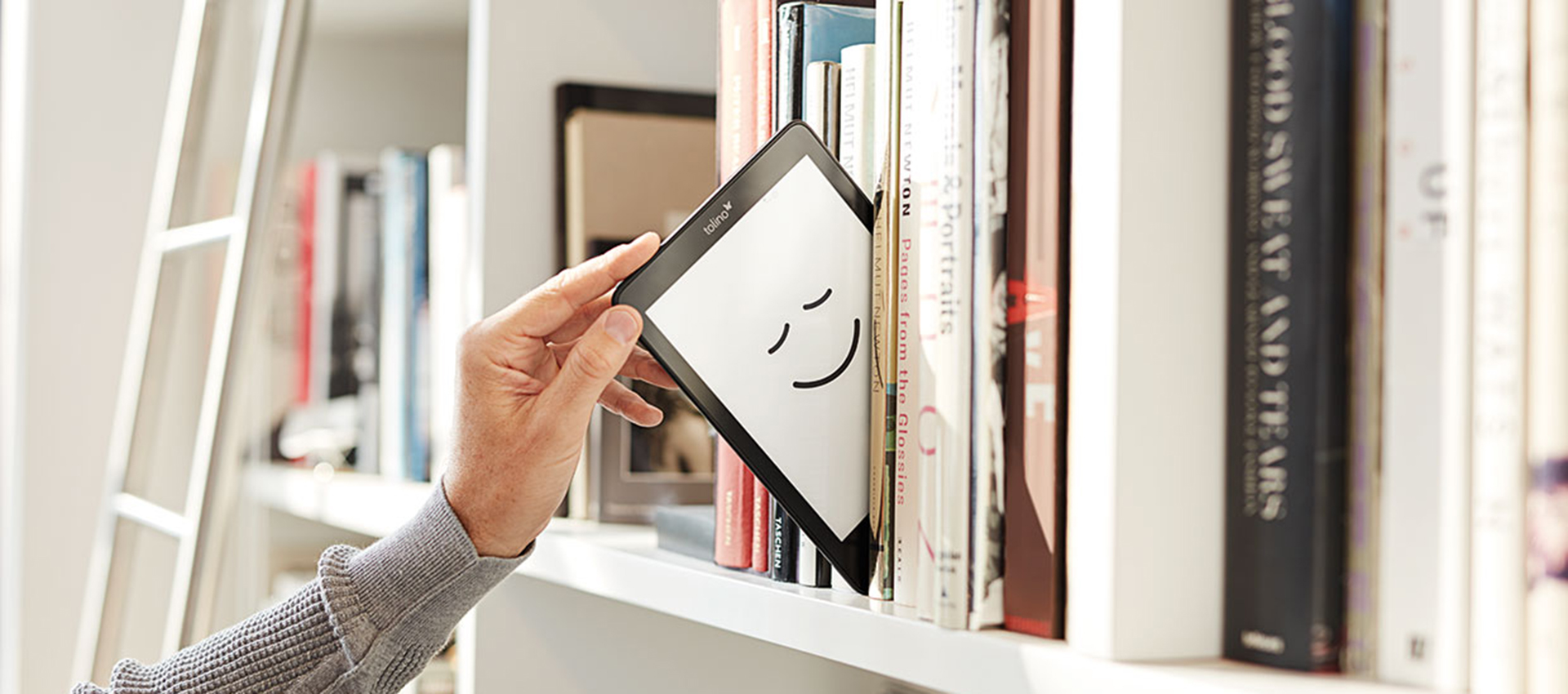 Männliche Hand zielt tolino-eReader aus Regal.