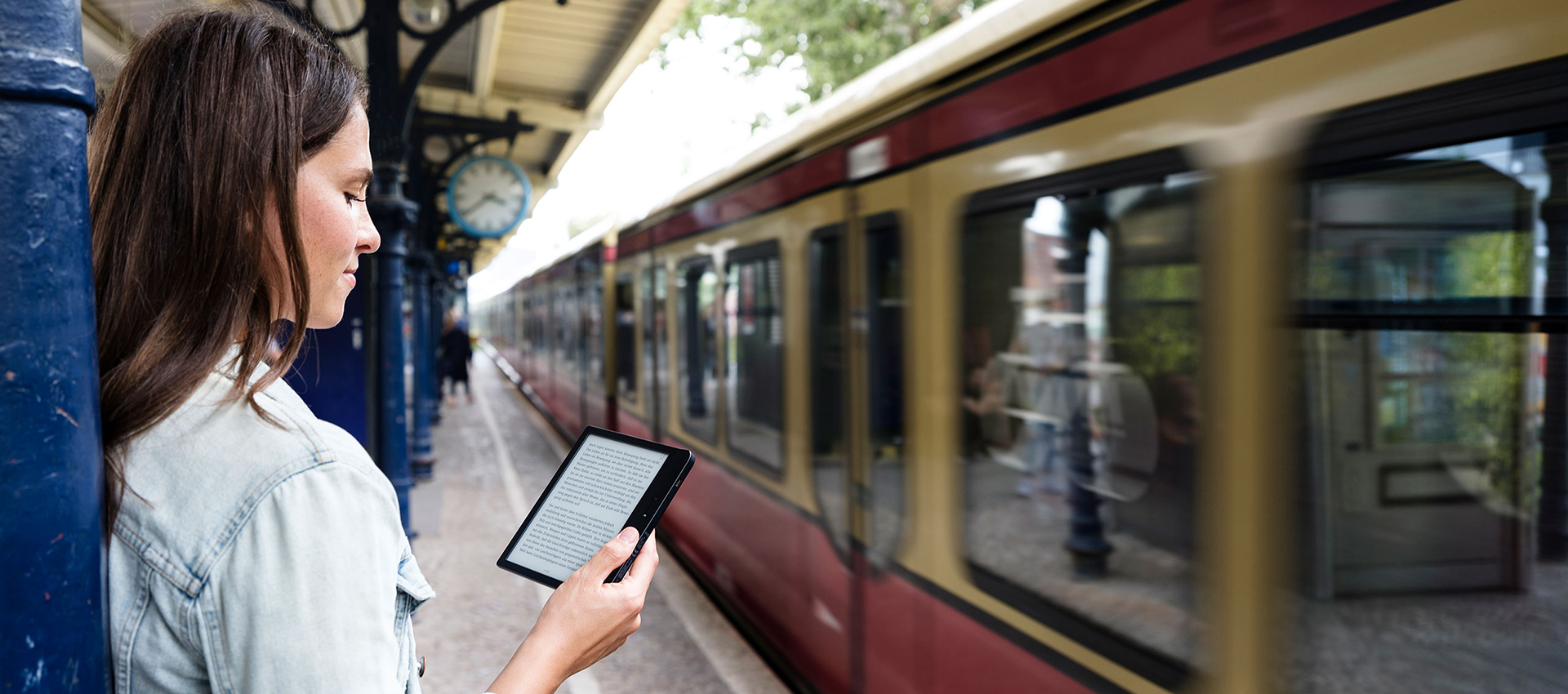 Junge Frau steht auf Bahnsteig mit tolino-eReader.